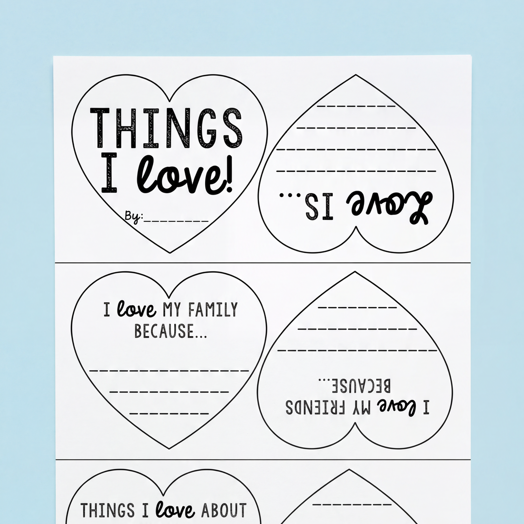 A completed "Things I Love" heart writing craft, showing a cut-out, colored, and assembled heart-shaped hanging decoration with handwritten responses. Surrounding materials include scissors and colourful paper.