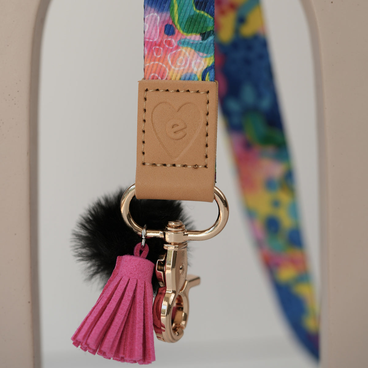 Detail of Love Fool teacher lanyard breakaway clasp, gold hardware with peach pom pom and orange tassel