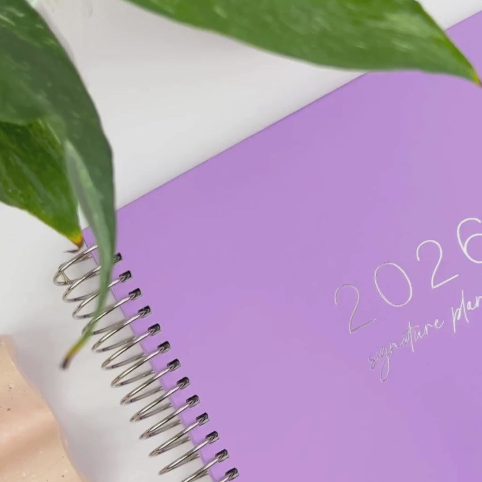 Front and back covers of the 2026 Lilac teacher planner being showcased on a white desk in a hands-on video demonstration.