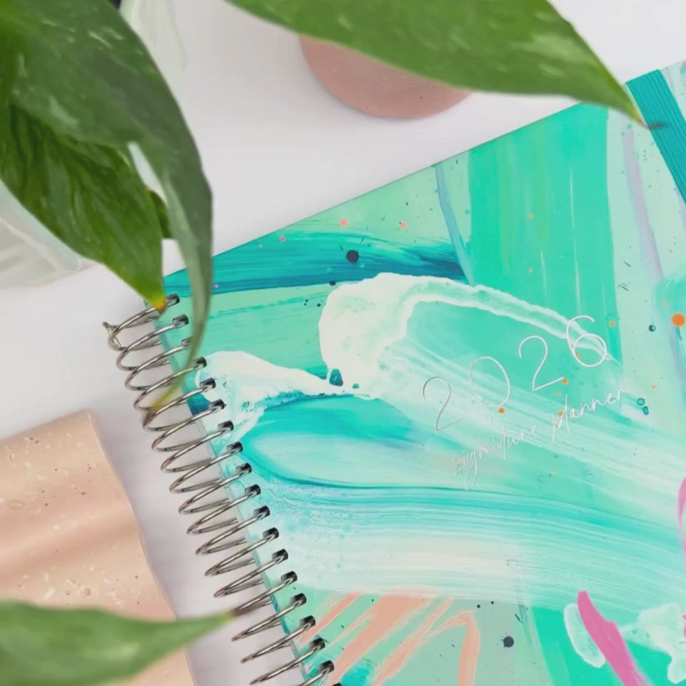 Front and back covers of the 2026 Paradise Island teacher planner being showcased on a white desk in a hands-on video demonstration.