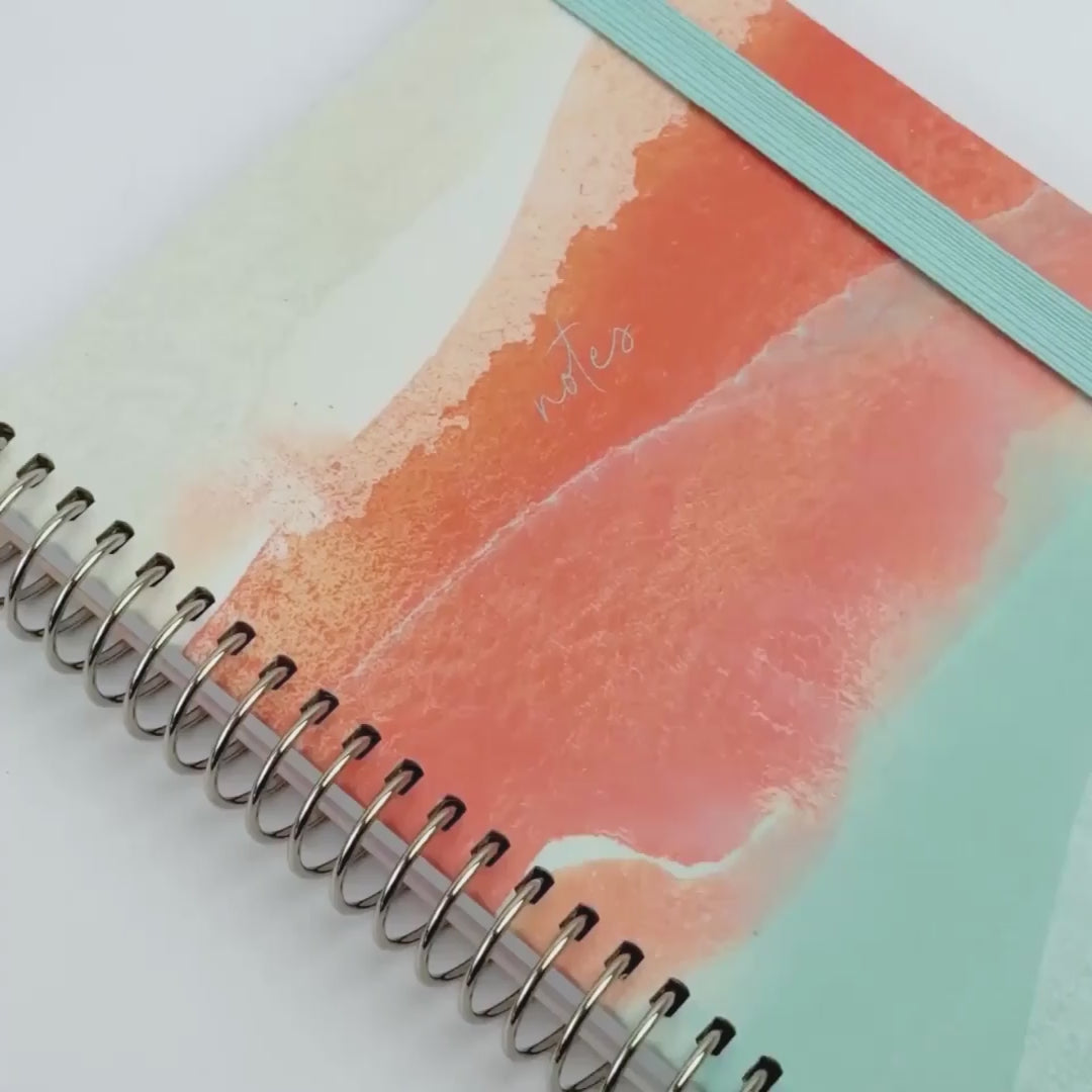 Notebook showing off Dreamy Afternoon design with blue elastic and silver binding