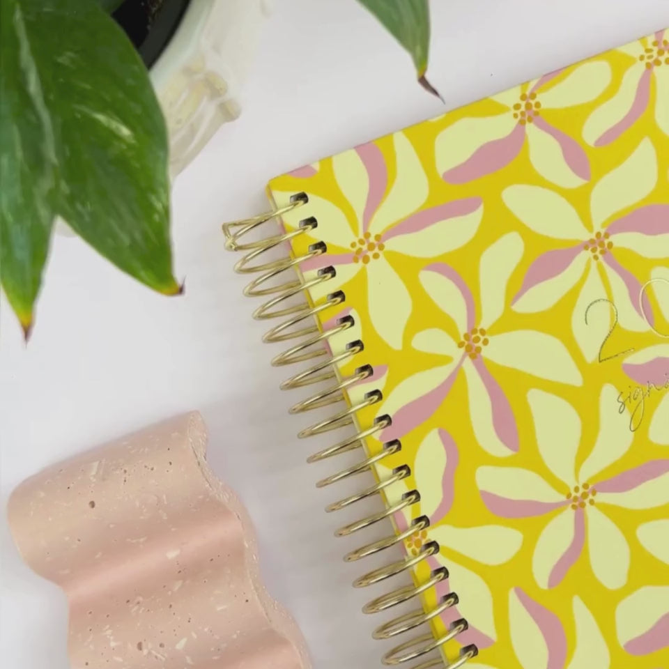 2026 Floral spell teacher planner cover being showcased on a white desk.