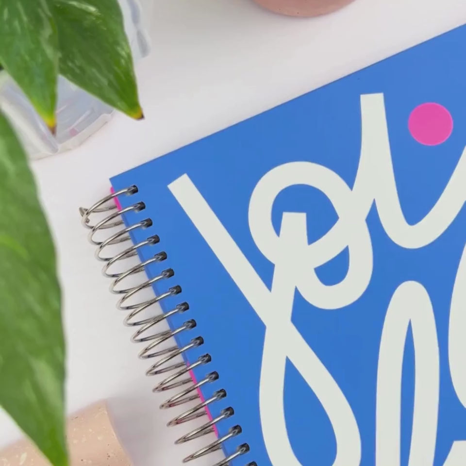 Front and back covers of the 2026 Joyful teacher planner being showcased on a white desk in a hands-on video demonstration.