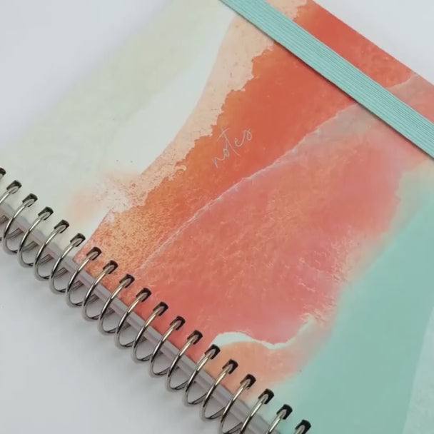 Notebook showing off Dreamy Afternoon design with blue elastic and silver binding