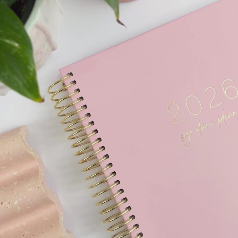 Hands Holding the 2026 Blush Weekly teacher planner, showing the front cover design and elastic page holder.