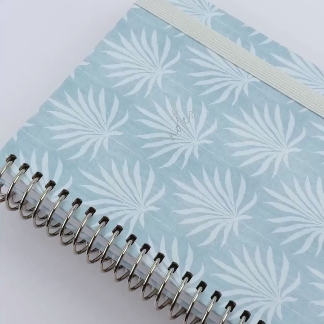 video of notebook light blue with a palm leaves designs 