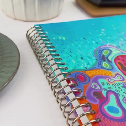 Front and back cover of the 2026 Reef Slimline teacher planner being showcased on a white desk in a hands-on video demonstration.