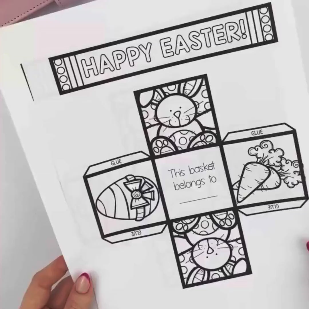 video showing a black-and-white printable Easter basket craft template on a sheet of paper. The template includes a “Happy Easter!” handle strip, foldable basket panels with bunny, egg, and carrot illustrations, glue tabs, and a section labeled “This basket belongs to.”