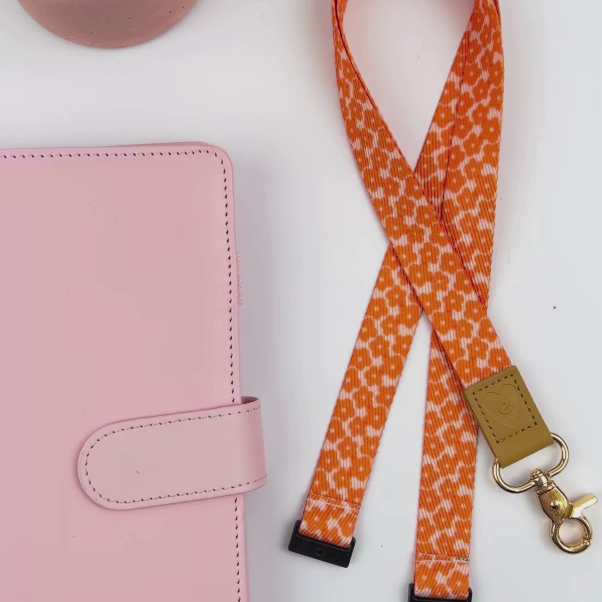 A women displays Tangerine Flowers lanyard with bright orange floral design, gold clasp, and tan leather accent detail.