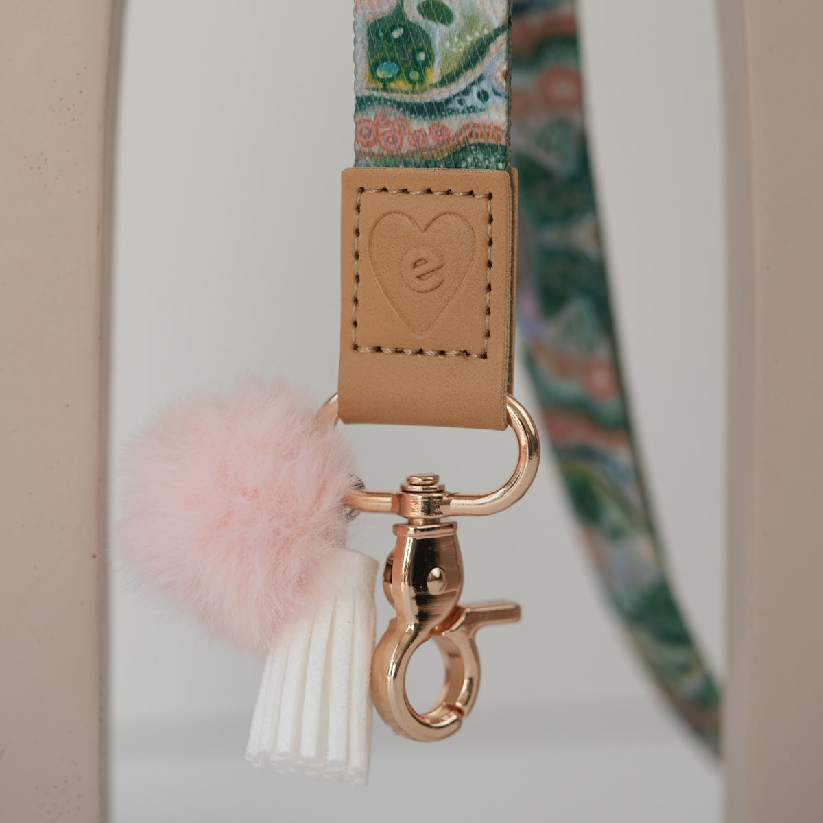 Detail of Sacred Grandparent Tree teacher lanyard clasp, gold hardware, peach pom pom and white tassel