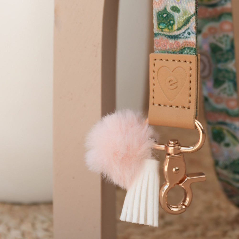 Close up of Sacred Grandparent Tree teacher lanyard artwork, gold clasp, peach pom pom and white tassel