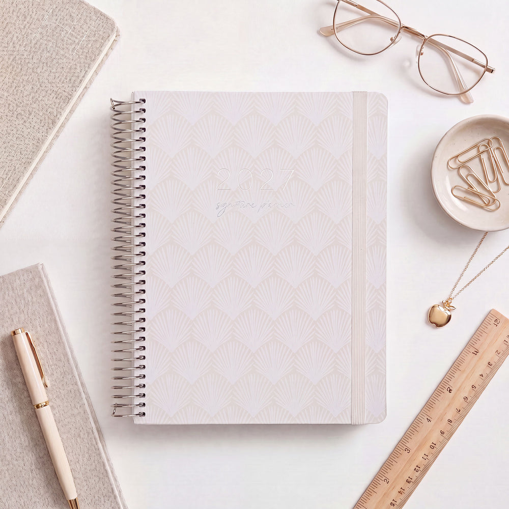 2027 Signature Planner in Shells styled with gold glasses and a wooden ruler, silver coil and cream elastic closure.