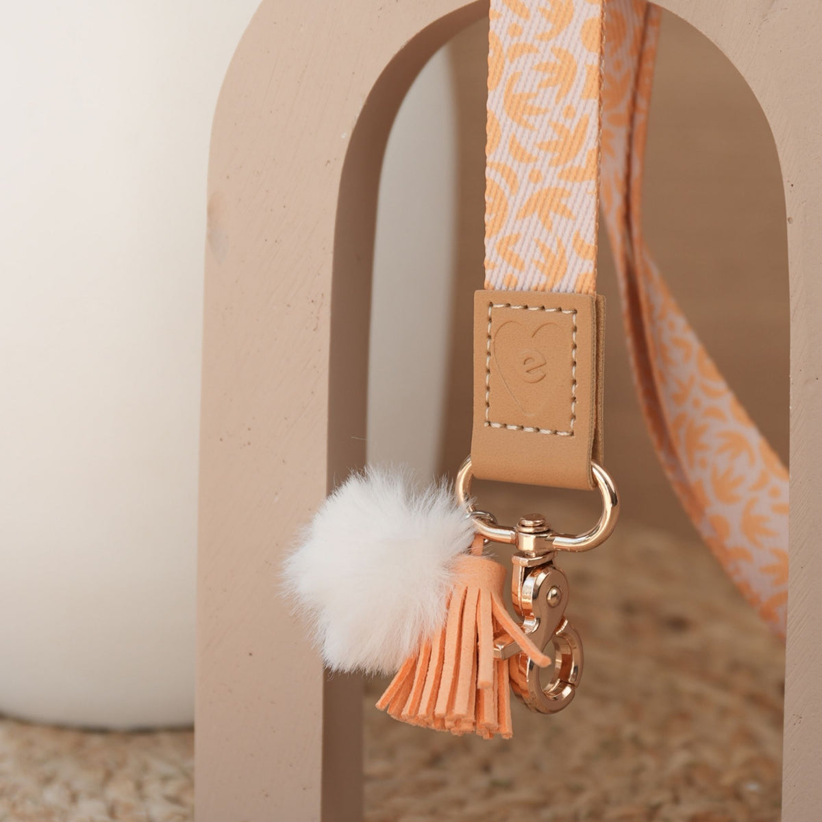 Close up of Sunburst Golden teacher lanyard, golden print, gold clasp, white pom pom and orange tassel