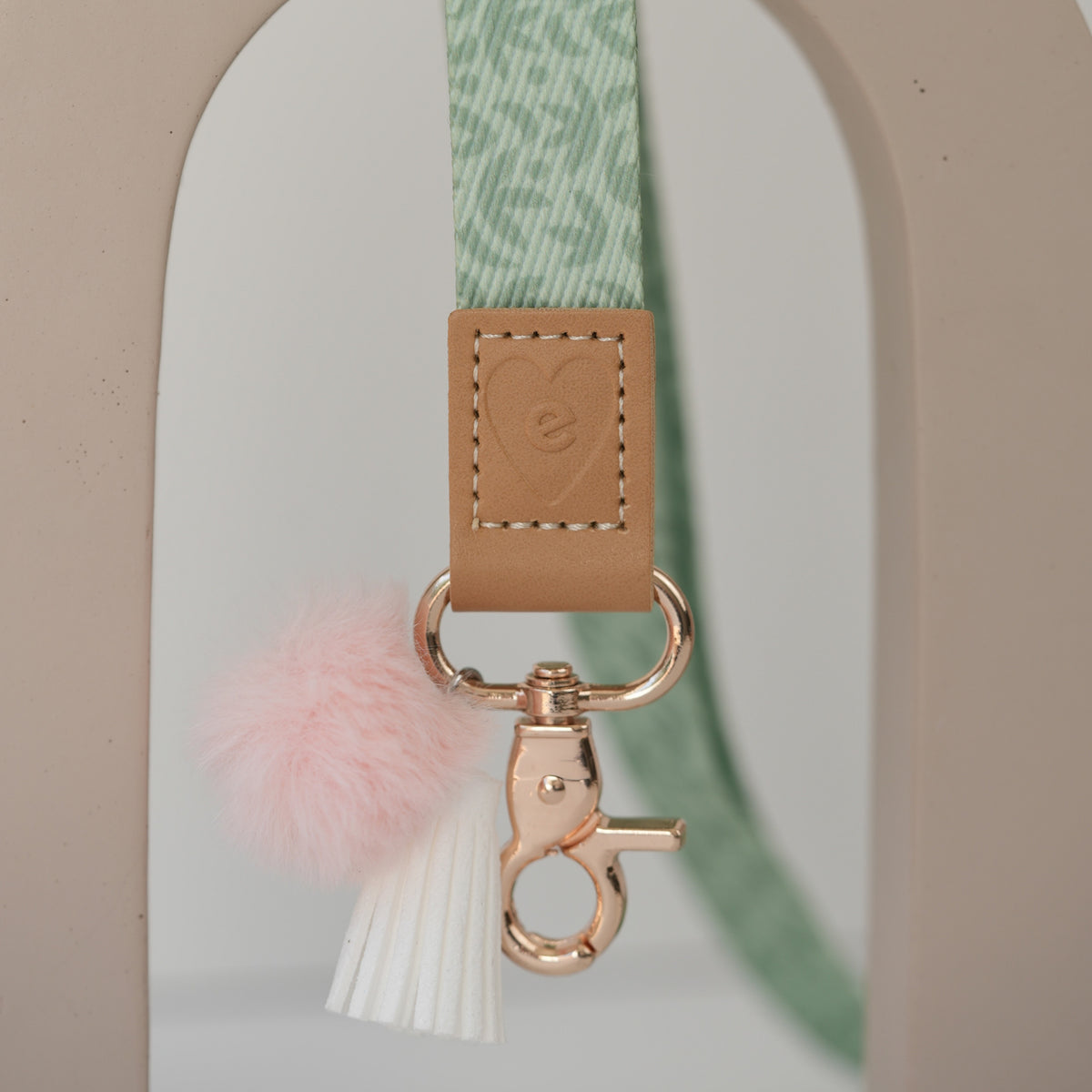 Detail of Sunburst Sage teacher lanyard breakaway clasp, gold hardware with peach pom pom and white tassel