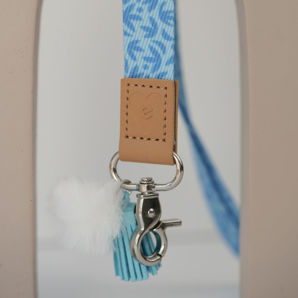 Detail of Sunburst Sky Blue teacher lanyard clasp, silver hardware with white pom pom and sky blue tassel