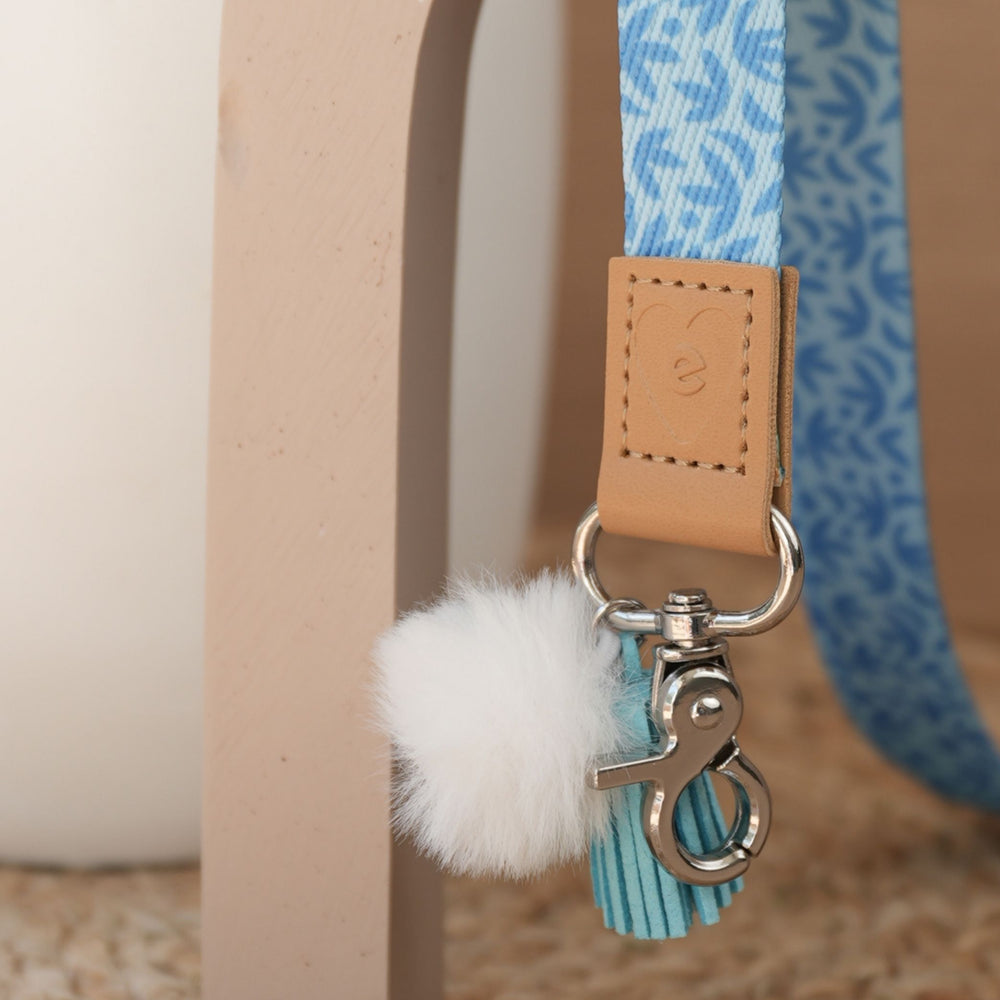 Close up of Sunburst Sky Blue teacher lanyard print, silver clasp, white pom pom and sky blue tassel