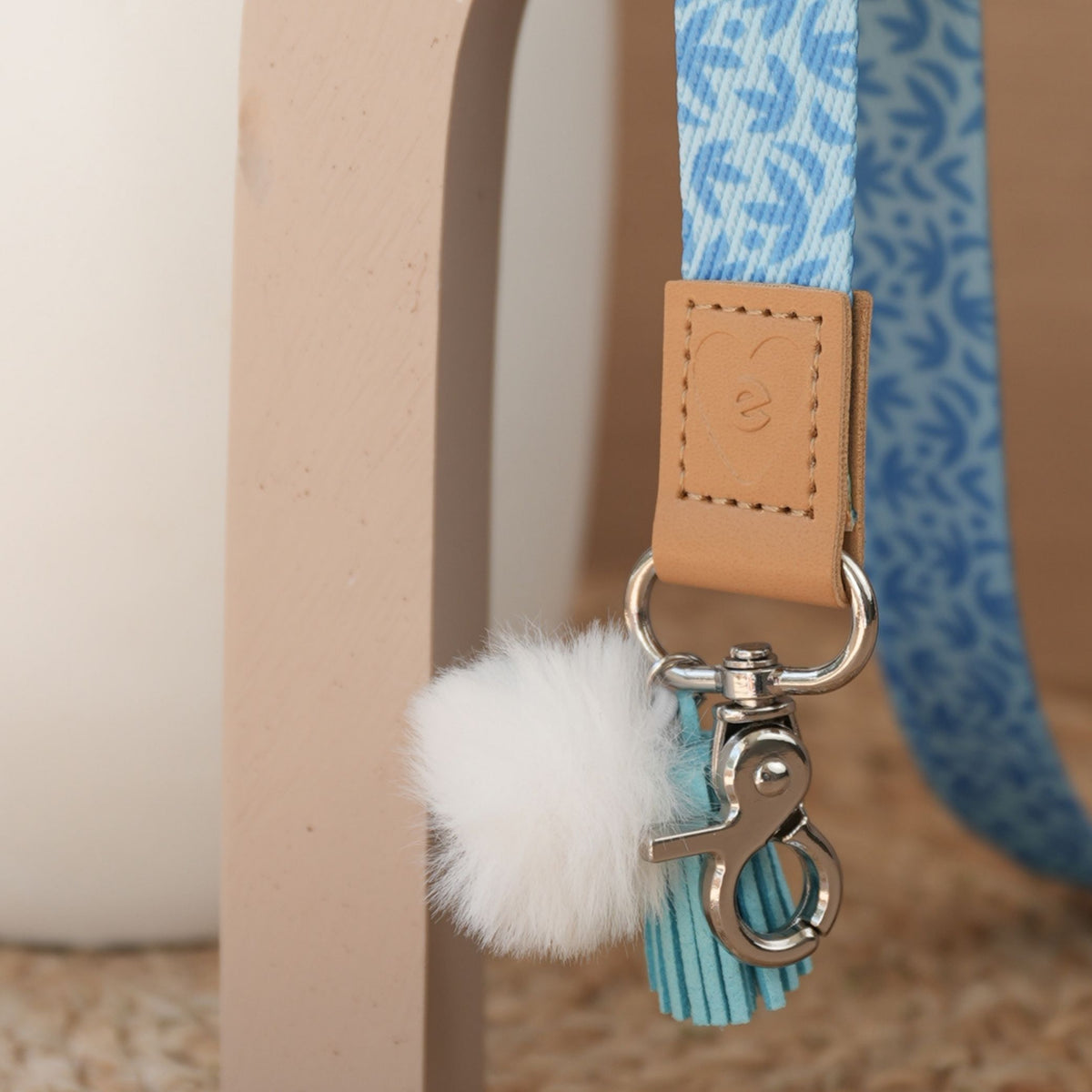 Close up of Sunburst Sky Blue teacher lanyard print, silver clasp, white pom pom and sky blue tassel