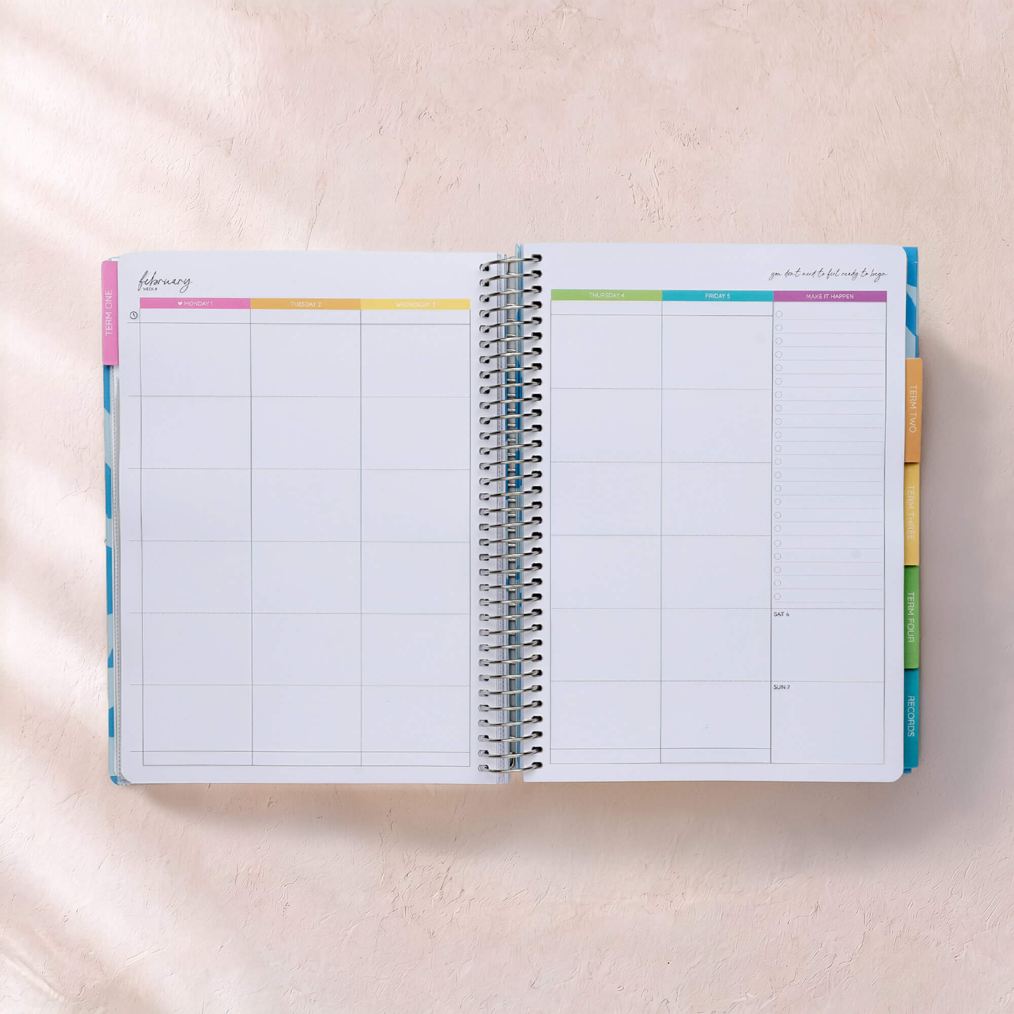 Open planner with colourful tabs on a light pink background